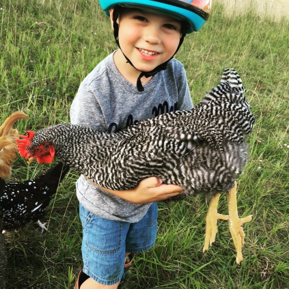 Our oldest holding a chicken in a break from riding his bike.